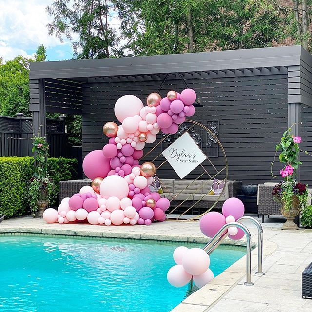 a pool decorated with balloons and streamers in the shape of a letter k is next to a swimming pool