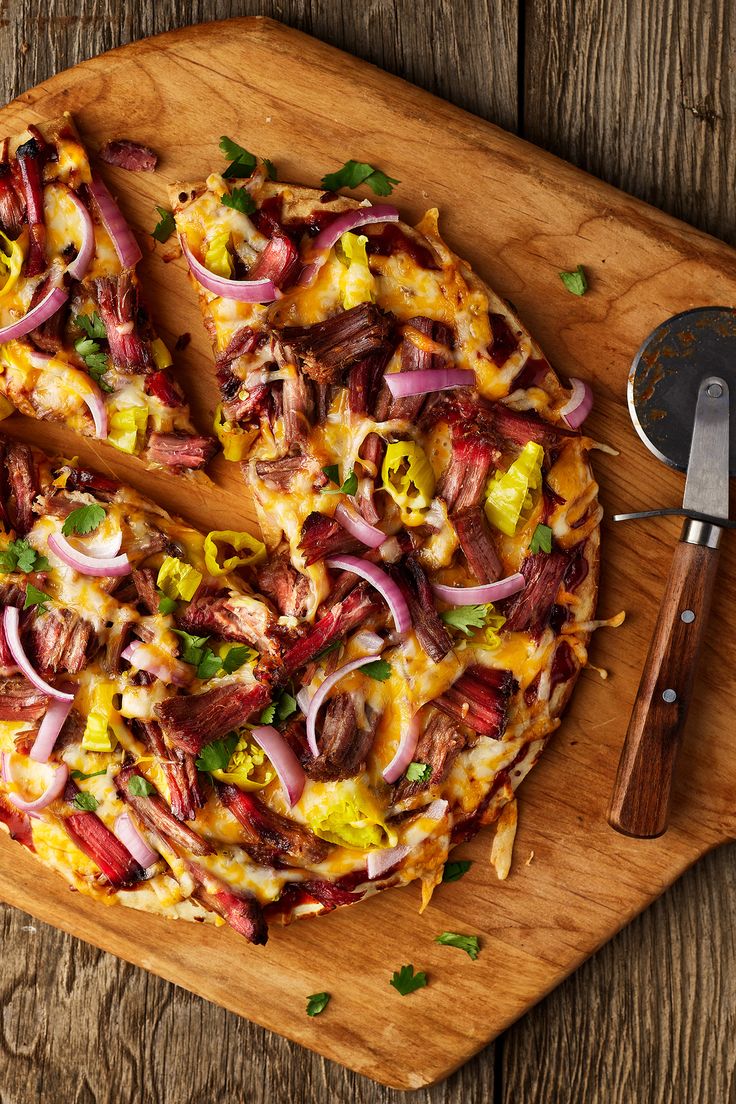 a pizza sitting on top of a wooden cutting board next to a knife and spatula