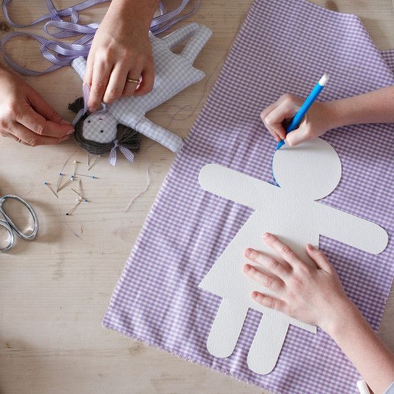 two people are making paper cutouts on a table with scissors and other crafting supplies