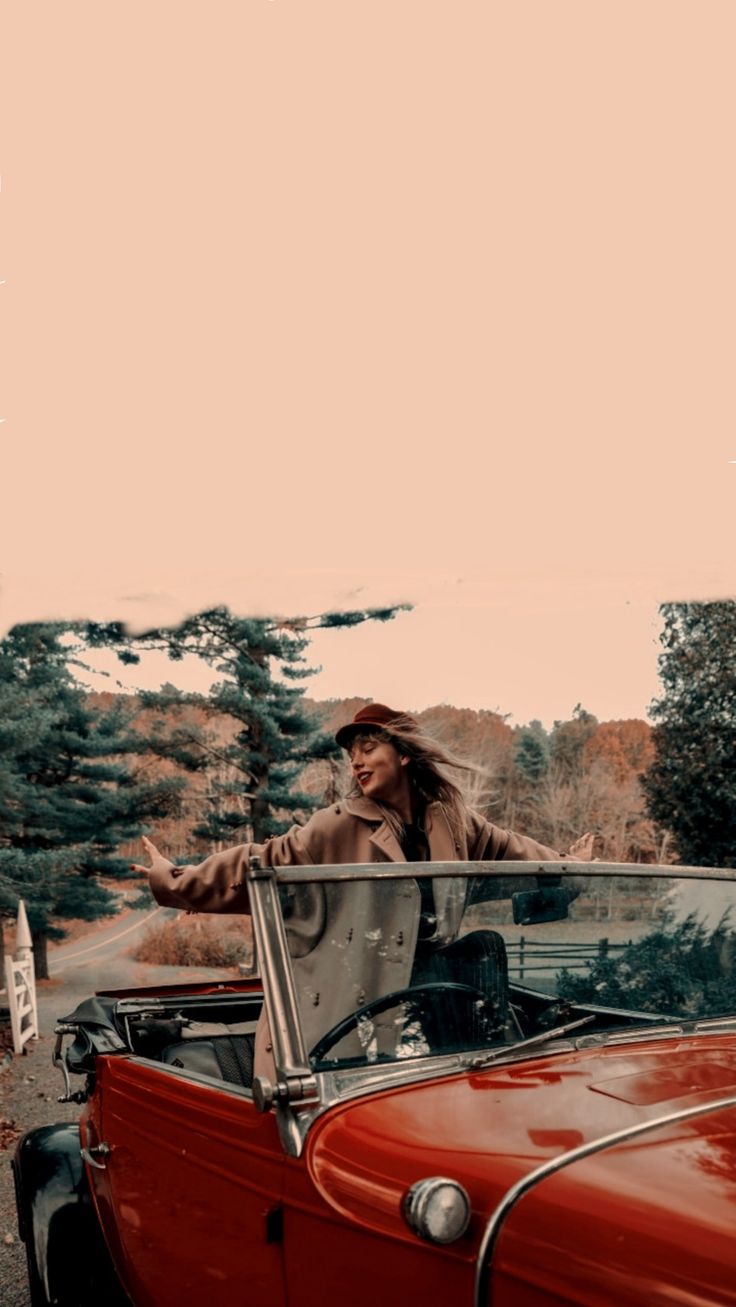 a man standing next to an old red car