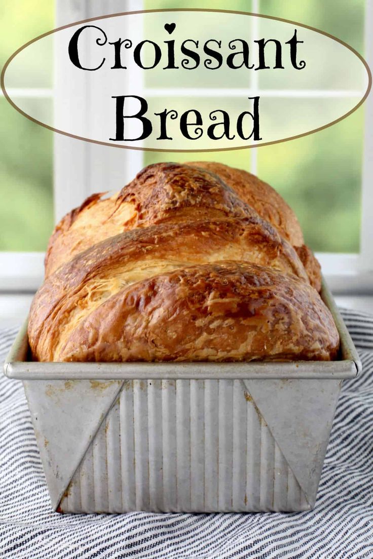 a loaf of bread sitting on top of a table next to a window with the words croissant bread