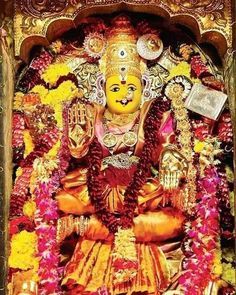 the idol of lord ganesha in front of an ornate shrine with flowers and garlands around it