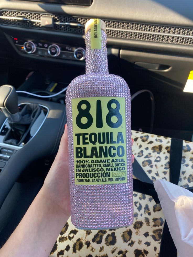 a person holding up a bottle of tequila in their hand with the number 818 on it