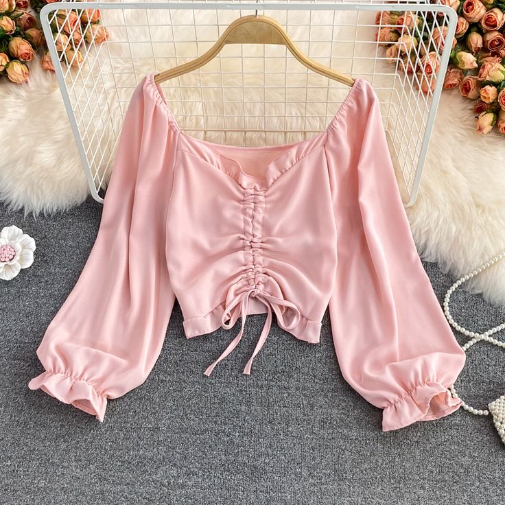 Introducing the Blush Pink Ruched Satin Blouse, a garment that exudes simple elegance and feminine charm. This piece is a must-have for those who appreciate the delicate interplay of soft fabric and subtle detailing. The blouse features a lustrous satin finish in a gentle blush pink hue that complements a wide range of complexions and adds a touch of romance to your ensemble.The design boasts a flattering off-the-shoulder neckline that transitions into long, billowing sleeves, cinched at the wri Feminine Cropped Blouse For Brunch, Elegant Ruched Crop Top, Chic Long Sleeve Padded Crop Top, Elegant Long Sleeve Padded Crop Top, Ruched Long Sleeve Crop Top For Party, Long Sleeve Ruched Crop Top For Summer, Long Sleeve Ruched Crop Top For Party, Trendy Long Sleeve Ruched Crop Top, Feminine Ruched Crop Top