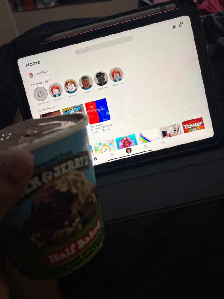 a person holding a cup of ice cream in front of a computer screen with stickers on it