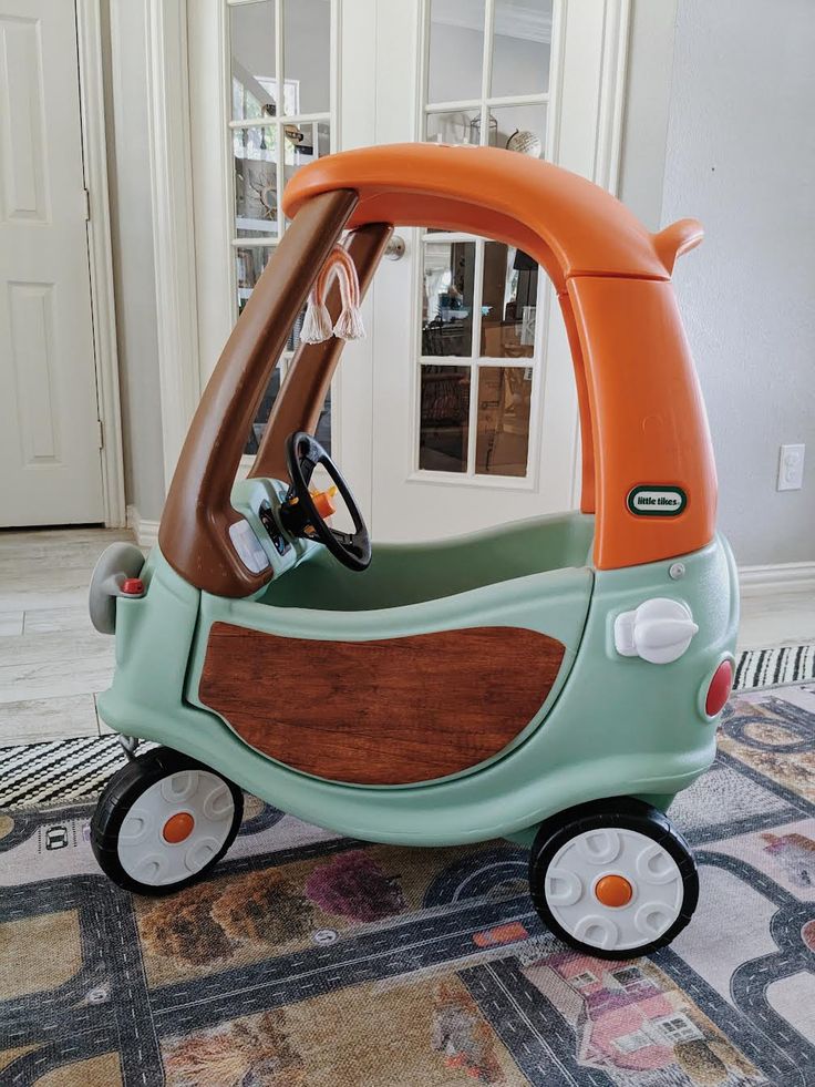 an orange and blue toy car on the floor in front of a white door with windows