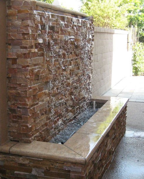 a water fountain in front of a brick wall