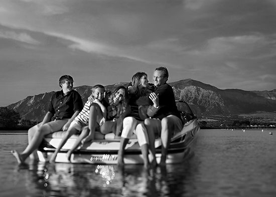 a group of people sitting on top of a boat in the water with mountains in the background