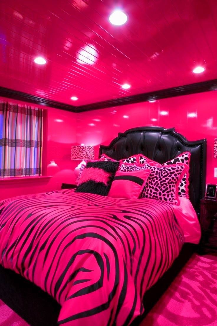 a bedroom decorated in pink and black with zebra print on the bedspread, pillows, and headboard