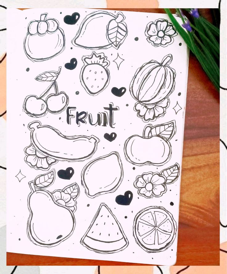 an open notebook with fruit drawn on it and flowers in the background next to it