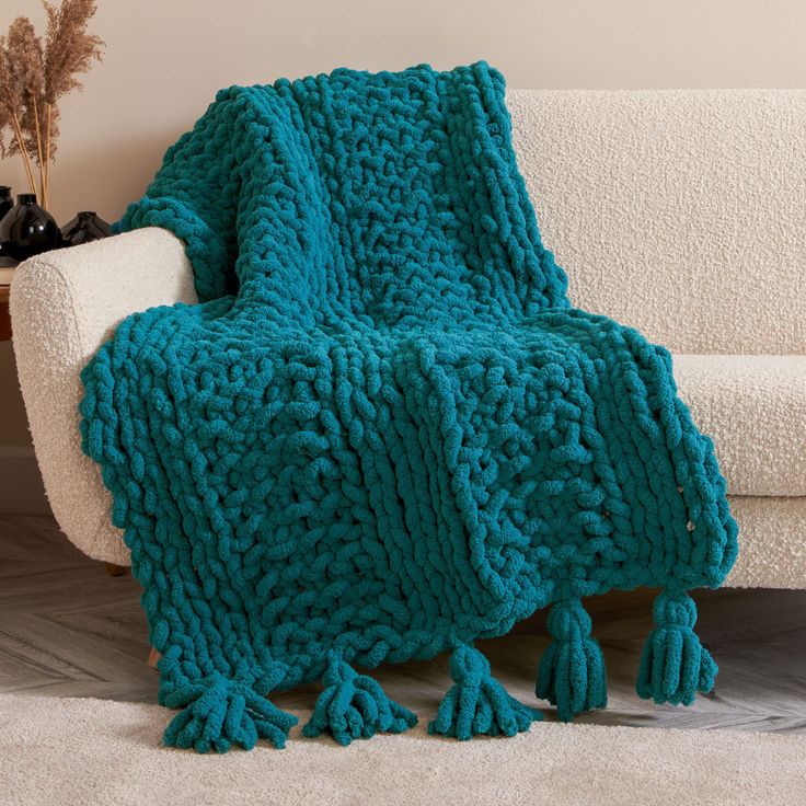 a blue knitted blanket sitting on top of a white couch