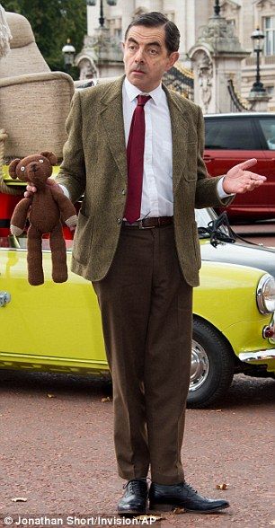 a man standing next to a yellow car with a teddy bear in it's hand