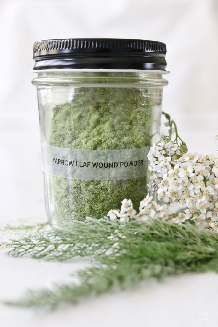 a jar filled with green powder next to flowers