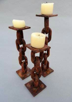 three candle holders made out of rusty metal chains with white candles on each one, sitting side by side