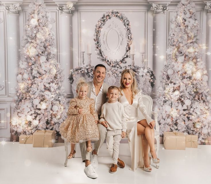 a family posing for a christmas photo in front of a decorated tree with presents on it