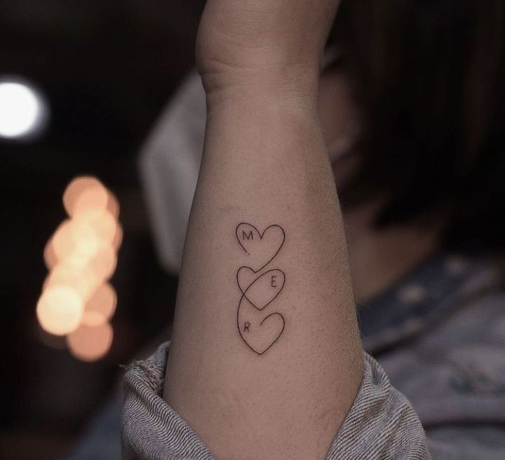 a woman's arm with two hearts tattooed on the left side of her arm