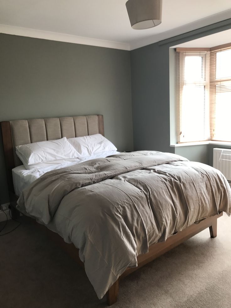 a bed sitting in the middle of a bedroom next to an air conditioner and window