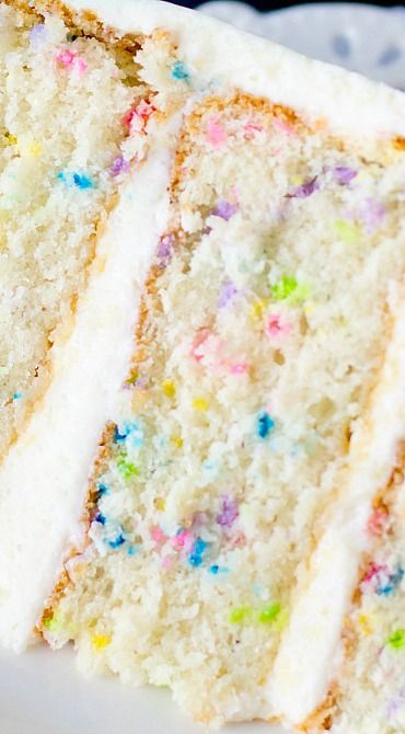 a slice of cake with white frosting and sprinkles