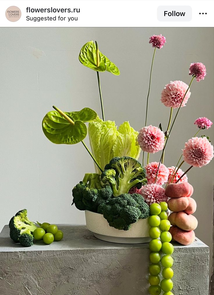 a vase filled with lots of flowers next to green beans and broccoli on top of a table