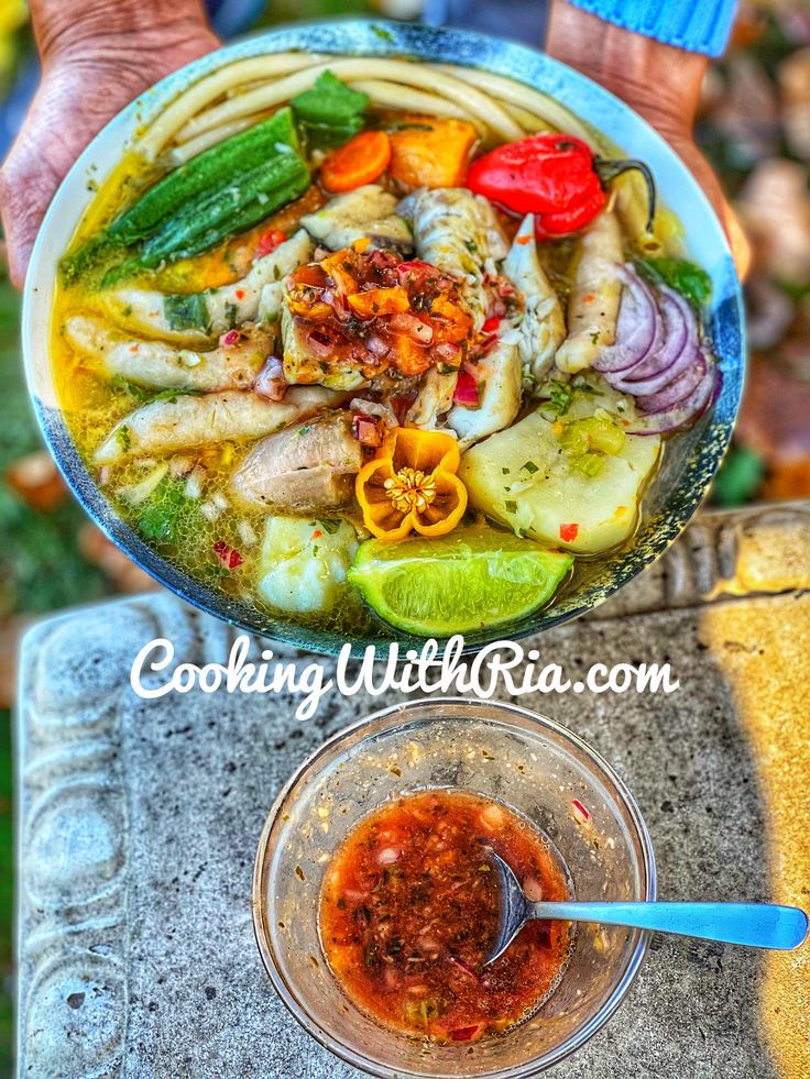 a person holding a bowl of food with sauce in it and another bowl filled with vegetables