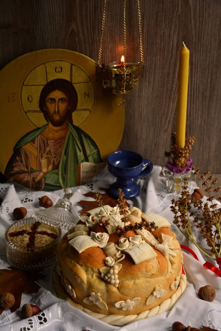 a table topped with a cake covered in icing next to a painting and candles