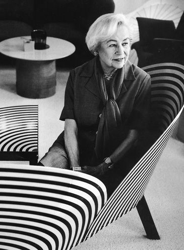 an older woman sitting in a chair with black and white stripes on it's sides