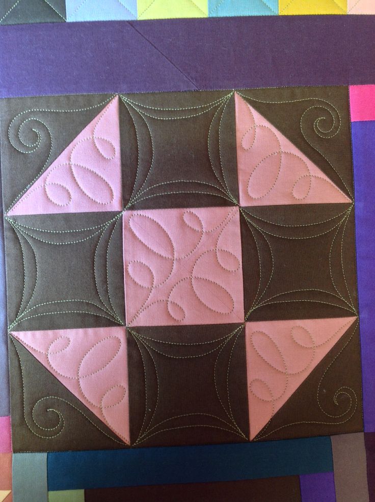 a piece of quilted material with pink and brown squares in the center, on top of multi - colored blocks