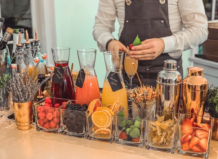 a person standing behind a counter filled with different types of drinks and condiments