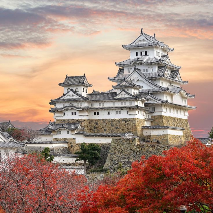 the castle is surrounded by trees with red and yellow leaves on it's sides