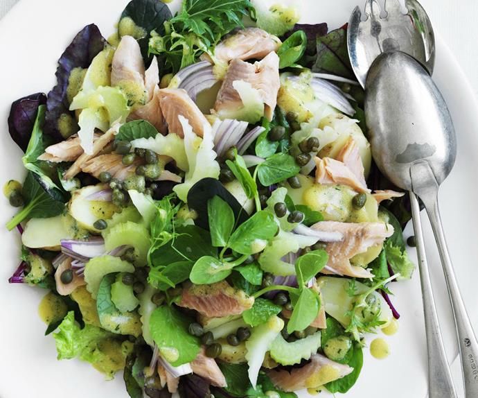 a white plate topped with salad covered in meat and veggies next to a spoon