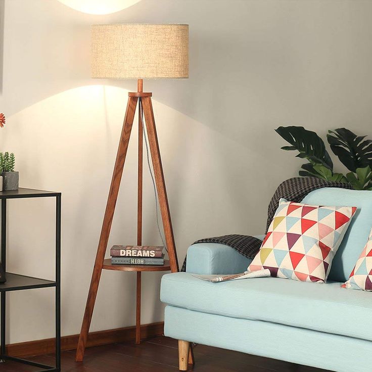 a living room with a blue couch and wooden floor lamp