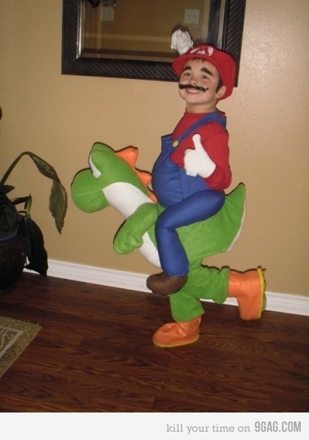 a man in a mario costume is riding on a toy alligator while standing next to a potted plant