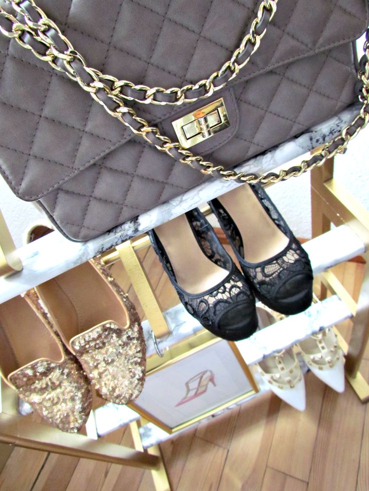 a woman's shoes and handbag sitting on top of a stand with gold chains