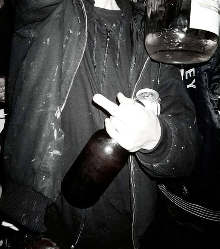 a man holding a beer in his right hand and wearing a leather jacket on the other