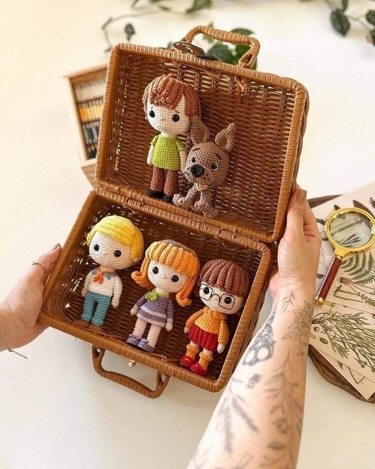 a person holding a wicker box with miniature figurines in it