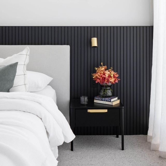 a black and white bedroom with flowers on the nightstand next to the bed in front of the window