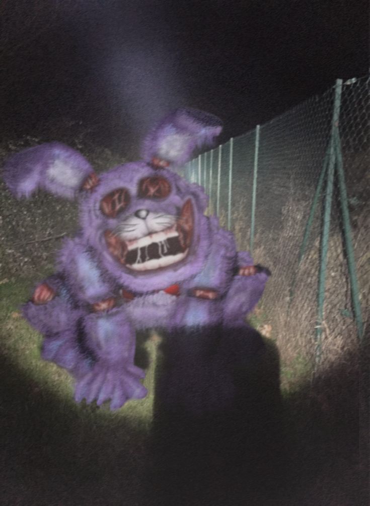 a purple stuffed animal standing next to a fence