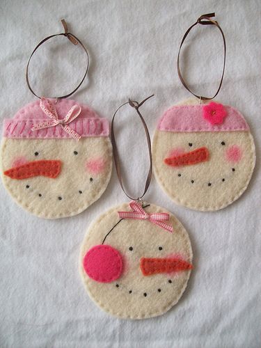 three ornaments are hanging on a white cloth covered tablecloth with pink and red designs