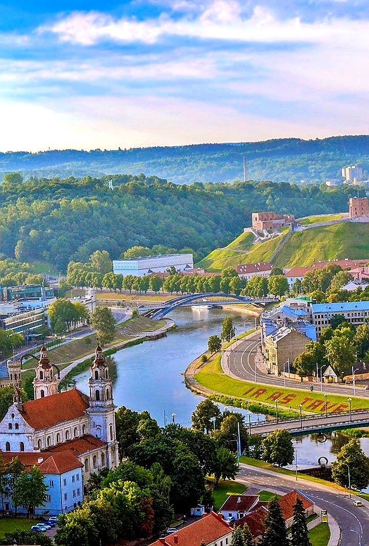 an aerial view of a town and river in the middle of a valley with trees on both sides