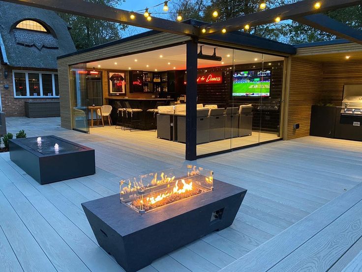 a fire pit sitting on top of a wooden deck next to a bar and grill