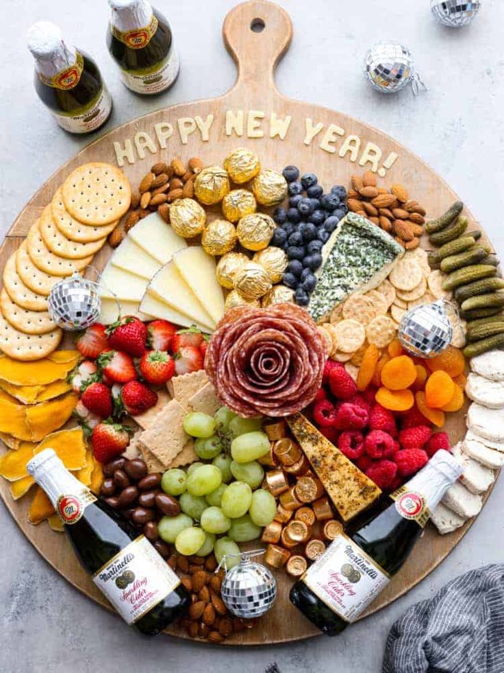 a wooden platter filled with different types of cheese and crackers next to bottles of wine