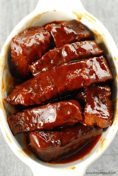 a bowl filled with meat and sauce on top of a gray tableclothed surface