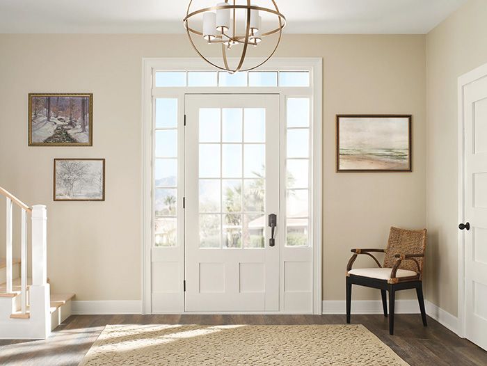 an empty entryway with a chair and pictures on the wall above it in front of a door