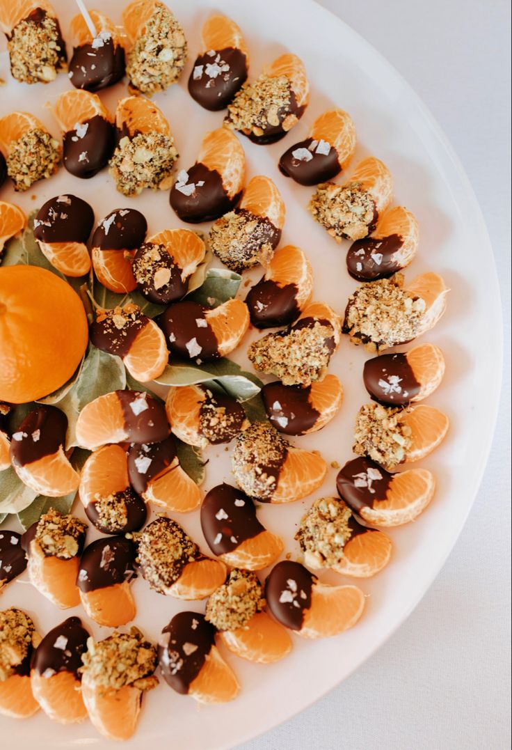 a white plate topped with oranges and chocolate candies on top of each other