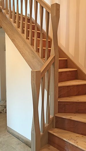 a wooden stair case next to a white wall