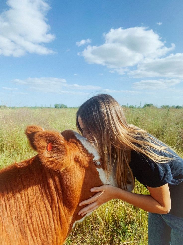 a woman is kissing the nose of a cow