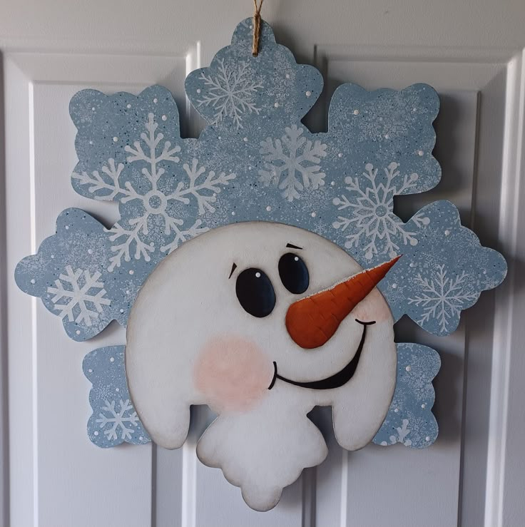 a snowman ornament hanging on a door with snowflakes in the background