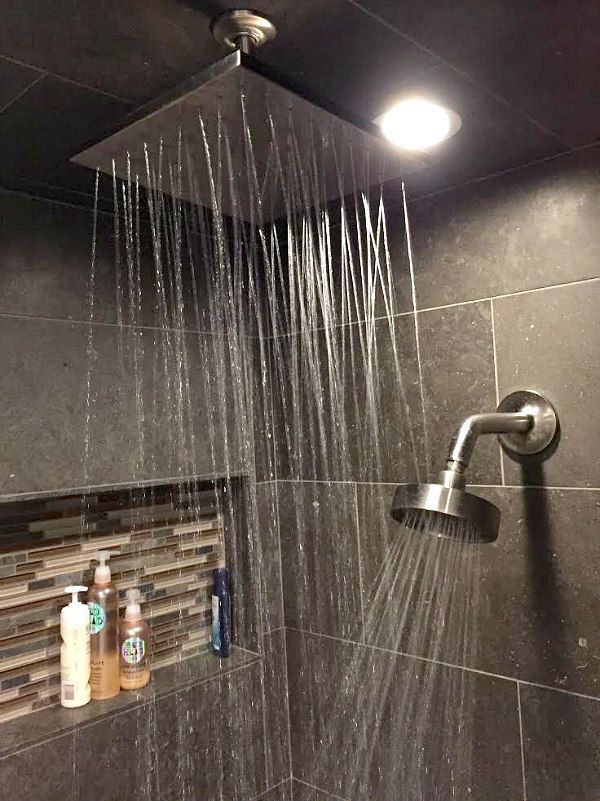 a shower head with water running down it's side and some bottles on the wall