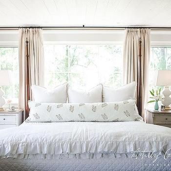 a bed with white sheets and pillows in a bedroom next to two lamps on either side of the bed