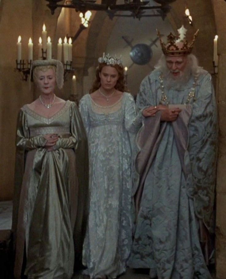 three women in dresses and tiaras standing next to each other with candles behind them